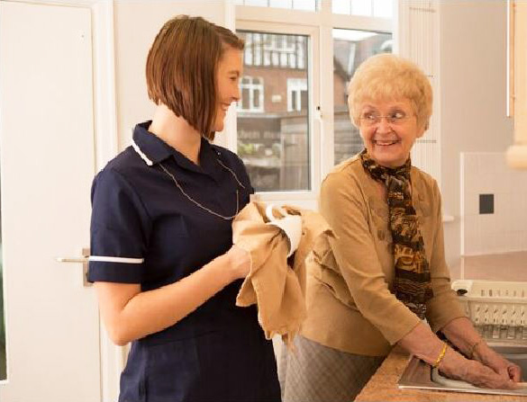 A homecare worker and an elder woman smiling each other